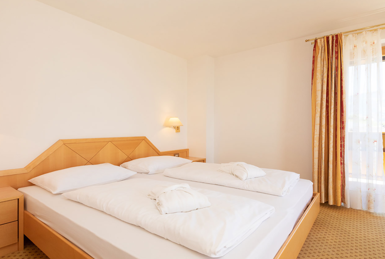 Schlafzimmer mit Doppelbett und Balkon der Hirzer Suite