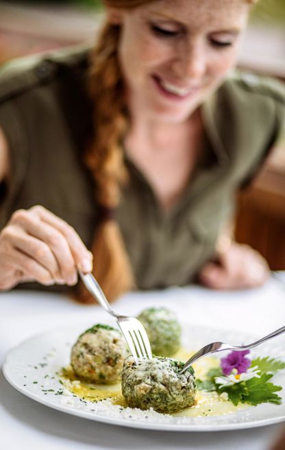 A woman is eating spinach dumplings