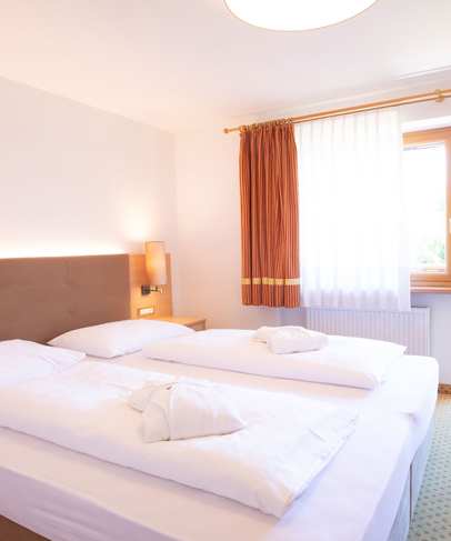 Schlafzimmer mit Doppelbett und Balkon der Mutspitz Superior Suite